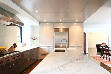 Inspiration for a large contemporary u-shaped medium tone wood floor eat-in kitchen remodel in Philadelphia with an undermount sink, flat-panel cabinets, light wood cabinets, marble countertops, white backsplash, glass tile backsplash, stainless steel appliances and an island