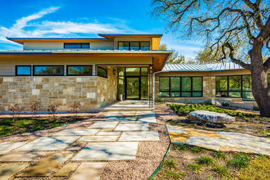 Inspiration for a large timeless beige two-story stone exterior home remodel in Austin with a metal roof
