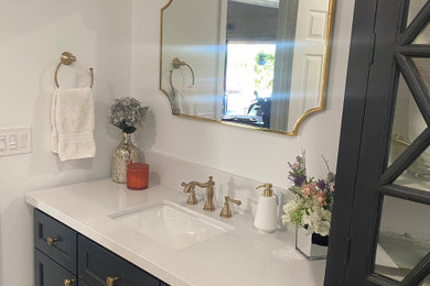 Example of a transitional black and white tile and ceramic tile porcelain tile, multicolored floor and single-sink bathroom design in Phoenix with black cabinets, a one-piece toilet, an undermount sink, quartz countertops, a hinged shower door, white countertops and a freestanding vanity