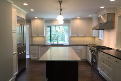 Large traditional u-shaped eat-in kitchen in Boston with an undermount sink, recessed-panel cabinets, white cabinets, quartz benchtops, white splashback, subway tile splashback, stainless steel appliances, dark hardwood floors and with island.
