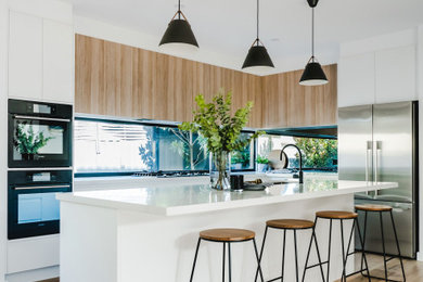 Design ideas for a mid-sized contemporary galley eat-in kitchen in Melbourne with white cabinets, with island and white benchtop.