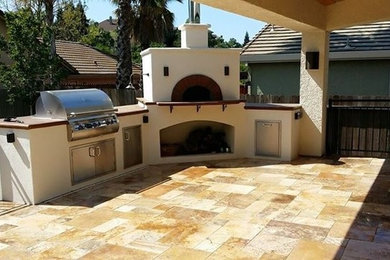 Large contemporary backyard patio in Sacramento with an outdoor kitchen, natural stone pavers and a roof extension.