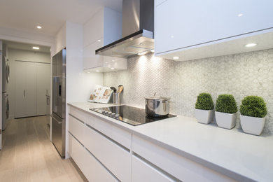 Eat-in kitchen - mid-sized contemporary galley light wood floor and beige floor eat-in kitchen idea in Vancouver with an undermount sink, flat-panel cabinets, white cabinets, quartz countertops, white backsplash, mosaic tile backsplash, stainless steel appliances, an island and white countertops