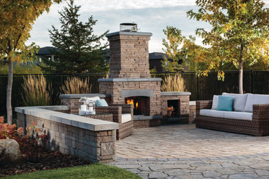 Diseño de patio en patio trasero con chimenea y adoquines de piedra natural