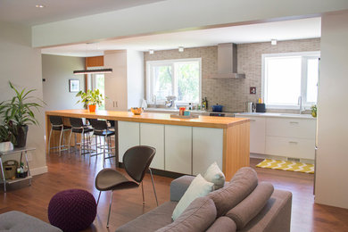 Open concept kitchen - mid-sized contemporary l-shaped dark wood floor open concept kitchen idea in Other with an undermount sink, flat-panel cabinets, white cabinets, wood countertops, stainless steel appliances, an island, gray backsplash and mosaic tile backsplash