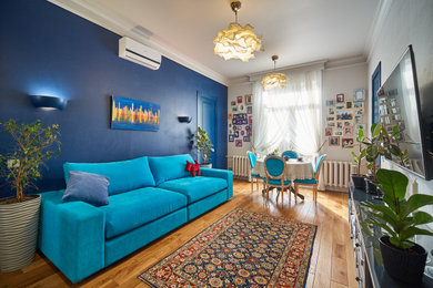 Пример оригинального дизайна: гостиная комната среднего размера в стиле неоклассика (современная классика) с синими стенами, паркетным полом среднего тона, телевизором на стене, коричневым полом и акцентной стеной