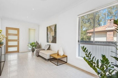 This is an example of a mid-sized modern foyer in Sydney with white walls, porcelain floors, a single front door and a light wood front door.