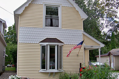 Mid-sized traditional yellow two-story wood exterior home idea in Other with a shingle roof