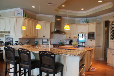 Large beach style u-shaped dark wood floor and brown floor eat-in kitchen photo in Tampa with beaded inset cabinets, beige cabinets, granite countertops, beige backsplash, ceramic backsplash, stainless steel appliances and two islands