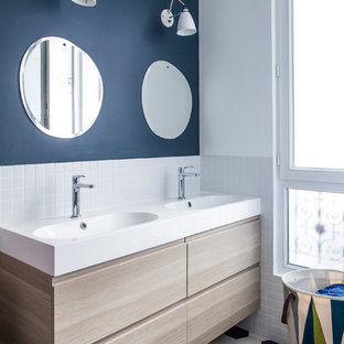 Idées déco pour une salle de bain contemporaine avec un placard à porte plane, des portes de placard en bois clair, un carrelage blanc, carrelage en mosaïque, un mur bleu, un plan vasque, un sol blanc et un plan de toilette blanc.