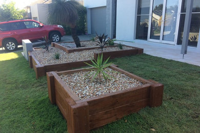 Design ideas for a mid-sized and australian native traditional front yard partial sun formal garden in Brisbane with a container garden and natural stone pavers.