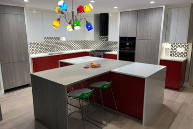 Mid-sized trendy l-shaped light wood floor eat-in kitchen photo in Portland with flat-panel cabinets, porcelain backsplash, stainless steel appliances and an island