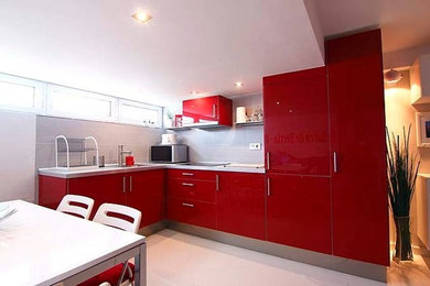 Design ideas for a mid-sized modern l-shaped open plan kitchen in Other with red cabinets, an integrated sink, flat-panel cabinets, ceramic splashback, panelled appliances, ceramic floors, white floor and grey benchtop.