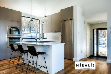 Example of a mid-sized minimalist l-shaped open concept kitchen design in Montreal with flat-panel cabinets, gray cabinets, quartz countertops, white backsplash, stainless steel appliances, an island and white countertops