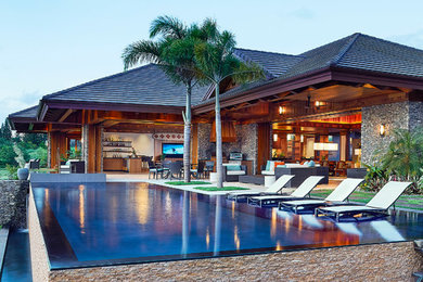 Large island style backyard rectangular and stone infinity hot tub photo in Hawaii