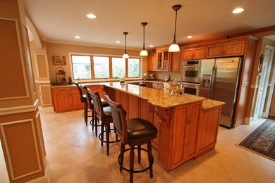 Eat-in kitchen - mid-sized traditional l-shaped ceramic tile and beige floor eat-in kitchen idea in Other with recessed-panel cabinets, light wood cabinets, granite countertops, beige backsplash, stone slab backsplash, stainless steel appliances, an island and an undermount sink