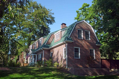 Ejemplo de fachada de casa clásica de dos plantas con revestimiento de ladrillo, tejado a doble faldón y tejado de teja de barro