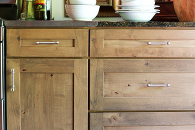 Example of a mid-sized danish l-shaped concrete floor eat-in kitchen design in Other with raised-panel cabinets, medium tone wood cabinets, granite countertops, stainless steel appliances and an island