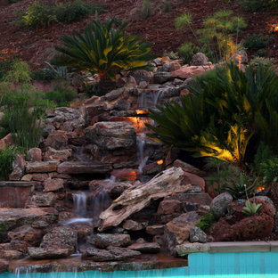Aménagement d'un grand jardin arrière montagne avec une exposition ensoleillée, des pavés en pierre naturelle et une cascade.