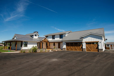 Large country white two-story exterior home photo in Other with a metal roof
