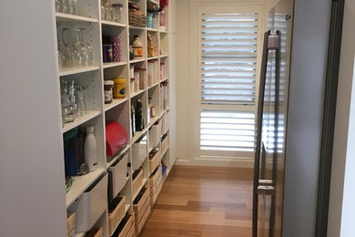 Design ideas for a large contemporary galley kitchen pantry in Canberra - Queanbeyan with an undermount sink, white cabinets, granite benchtops, white splashback, ceramic splashback, stainless steel appliances, medium hardwood floors, with island, multi-coloured floor and beige benchtop.