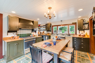 Elegant kitchen photo in New York with a farmhouse sink, black cabinets, wood countertops and stainless steel appliances