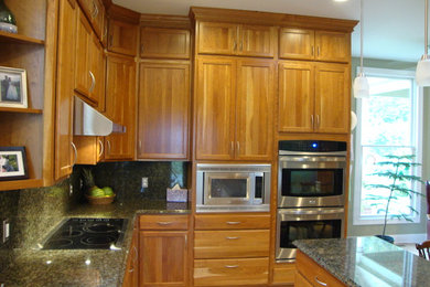Photo of a large contemporary u-shaped eat-in kitchen in Baltimore with light wood cabinets, granite benchtops, green splashback, stainless steel appliances, ceramic floors and with island.