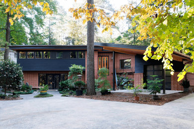 Mid-century modern red two-story brick house exterior photo in Raleigh with a shed roof