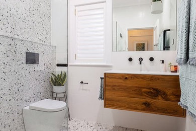 Inspiration for a mid-sized modern 3/4 wet room bathroom in Sydney with furniture-like cabinets, dark wood cabinets, a wall-mount toilet, black and white tile, stone tile, white walls, terrazzo floors, an integrated sink, engineered quartz benchtops, multi-coloured floor, a hinged shower door and white benchtops.