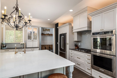Open concept kitchen - mid-sized transitional l-shaped dark wood floor and brown floor open concept kitchen idea in Portland with a farmhouse sink, flat-panel cabinets, gray cabinets, quartz countertops, blue backsplash, mosaic tile backsplash, stainless steel appliances, an island and white countertops