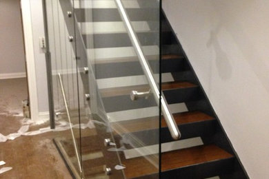 This is an example of a contemporary wood straight glass railing staircase in London with open risers.