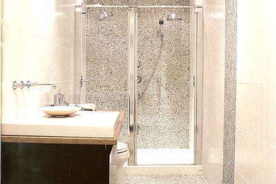 Inspiration for a large modern 3/4 gray tile and pebble tile pebble tile floor alcove shower remodel in Charlotte with flat-panel cabinets, black cabinets, beige walls, a vessel sink and wood countertops