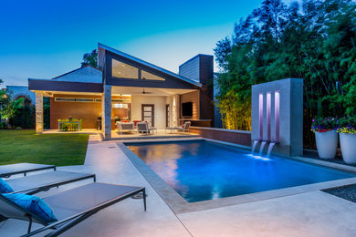 Photo of a large contemporary backyard rectangular pool in Dallas with a pool house and concrete pavers.