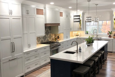 Inspiration for a large coastal l-shaped light wood floor and brown floor eat-in kitchen remodel in Other with a farmhouse sink, recessed-panel cabinets, gray cabinets, quartz countertops, gray backsplash, ceramic backsplash, stainless steel appliances, an island and white countertops
