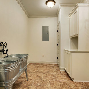 ニューオリンズの中サイズのラスティックスタイルのおしゃれな家事室 (レイズドパネル扉のキャビネット、白いキャビネット、木材カウンター、白い壁、セラミックタイルの床、左右配置の洗濯機・乾燥機) の写真