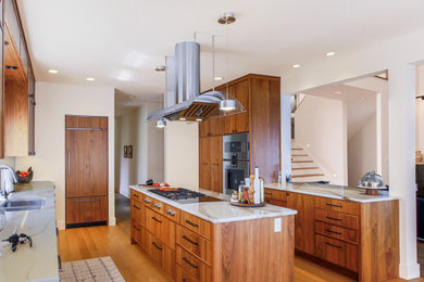 Design ideas for a mid-sized eclectic galley eat-in kitchen in Seattle with a double-bowl sink, medium wood cabinets, quartz benchtops, ceramic splashback, stainless steel appliances, light hardwood floors, with island, brown floor, white benchtop, white splashback and flat-panel cabinets.