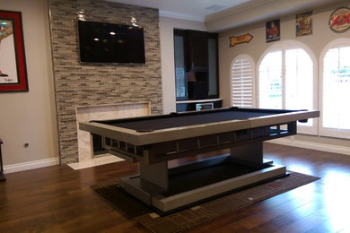 Inspiration for a contemporary medium tone wood floor game room remodel in Orange County with beige walls, a standard fireplace, a tile fireplace and a wall-mounted tv