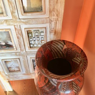 Esempio di una camera matrimoniale etnica di medie dimensioni con pareti arancioni, pavimento in laminato, nessun camino e pavimento marrone