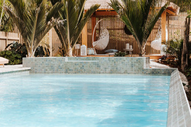 Diseño de casa de la piscina y piscina tropical grande rectangular en patio delantero con adoquines de piedra natural
