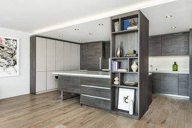 Inspiration for a contemporary l-shaped medium tone wood floor and brown floor kitchen remodel in San Francisco with flat-panel cabinets, gray cabinets, paneled appliances, an island and white countertops