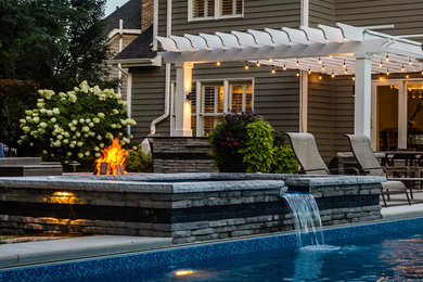 Inspiration for a large contemporary backyard concrete paver patio remodel in Chicago with a fire pit and a pergola