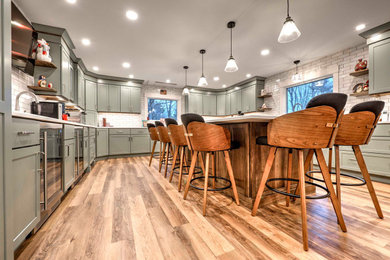 Eat-in kitchen - large u-shaped eat-in kitchen idea in Other with a farmhouse sink, shaker cabinets, white backsplash, porcelain backsplash, stainless steel appliances and an island