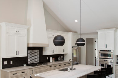 This is an example of a large transitional l-shaped open plan kitchen in St Louis with an undermount sink, recessed-panel cabinets, white cabinets, quartz benchtops, black splashback, ceramic splashback, stainless steel appliances, light hardwood floors, with island, beige floor and white benchtop.