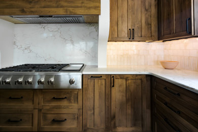 Eat-in kitchen - southwestern l-shaped medium tone wood floor and brown floor eat-in kitchen idea in Other with shaker cabinets, medium tone wood cabinets, quartz countertops, white backsplash, porcelain backsplash, an island and white countertops
