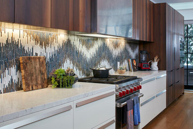 Example of a large trendy galley medium tone wood floor and brown floor enclosed kitchen design in New York with flat-panel cabinets, dark wood cabinets, quartz countertops, multicolored backsplash, mosaic tile backsplash, stainless steel appliances, an island and gray countertops