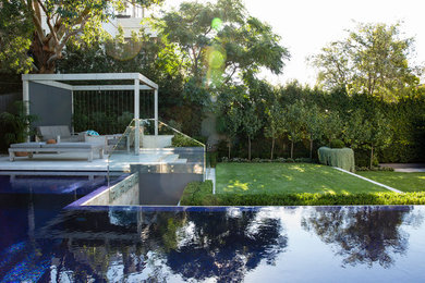 Inspiration for a large modern backyard rectangular lap pool in Sydney with concrete pavers.