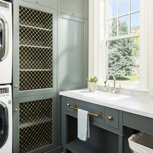 Inspiration for a classic separated utility room in Salt Lake City with a single-bowl sink, shaker cabinets, grey cabinets, a stacked washer and dryer and grey floors.