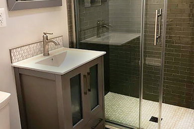 Small transitional 3/4 bathroom in DC Metro with glass-front cabinets, grey cabinets, an alcove shower, a two-piece toilet, gray tile, glass sheet wall, white walls, ceramic floors, an integrated sink, grey floor and a sliding shower screen.