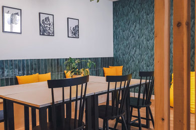 Cette photo montre une petite salle à manger ouverte sur le salon industrielle avec un mur vert, sol en stratifié, un sol beige et du papier peint.