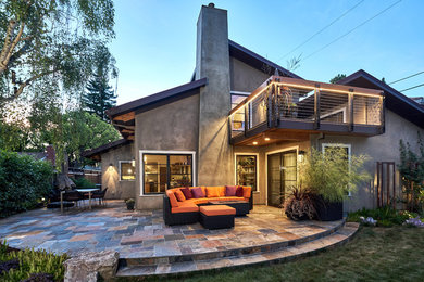 Large contemporary backyard deck in San Francisco with a fire feature and a roof extension.
